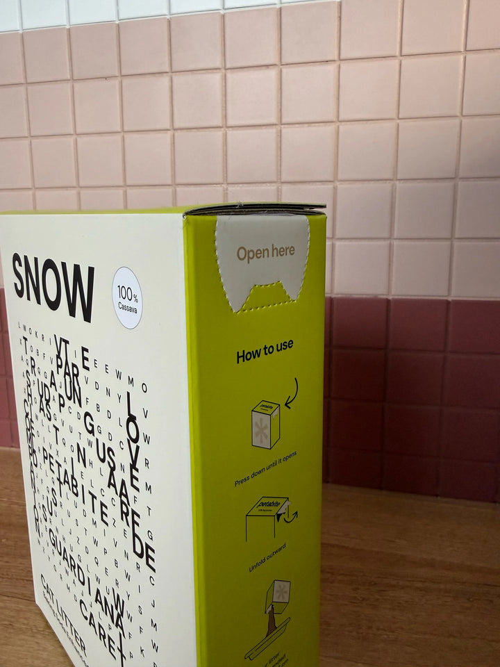 Snow box with open tab and side instructions against a tiled wall