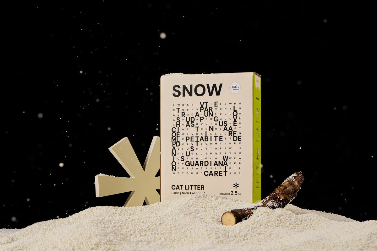 A Snow cat litter box with cassava root and granules against a black studio background